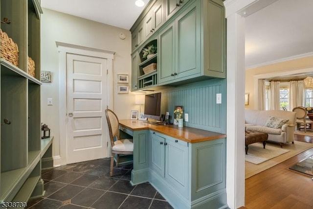 tiled office space with crown molding and built in desk