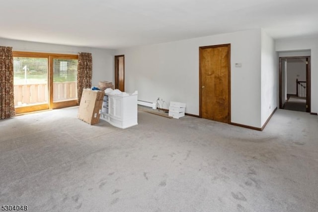 carpeted spare room with a baseboard heating unit