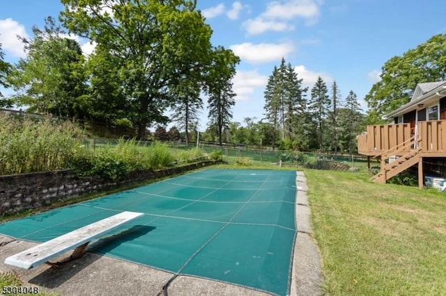 view of swimming pool featuring a yard and a diving board