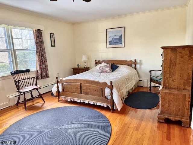 bedroom featuring hardwood / wood-style floors, crown molding, and a baseboard heating unit