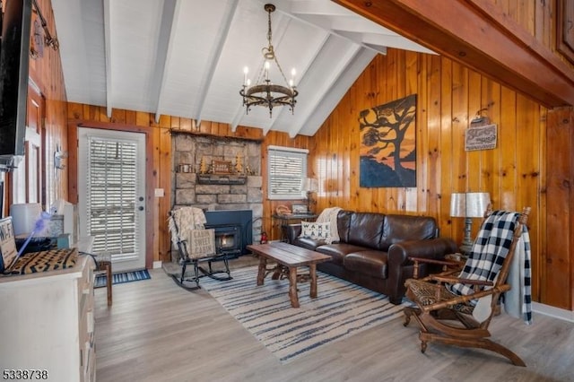 living area featuring lofted ceiling with beams, an inviting chandelier, wooden walls, and wood finished floors