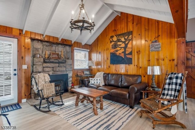 living room featuring lofted ceiling with beams, wooden walls, wood finished floors, and a notable chandelier