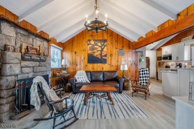 living area with a large fireplace, wooden walls, light wood-style flooring, vaulted ceiling with beams, and a chandelier