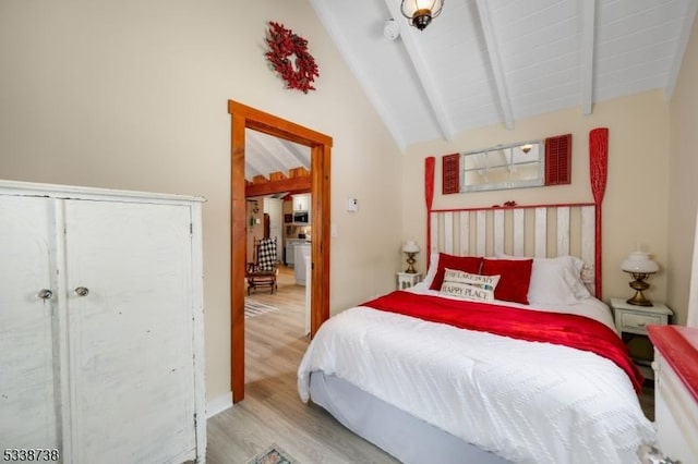 bedroom with lofted ceiling with beams and light wood-type flooring