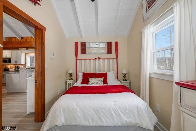 bedroom featuring light wood-style floors and vaulted ceiling with beams