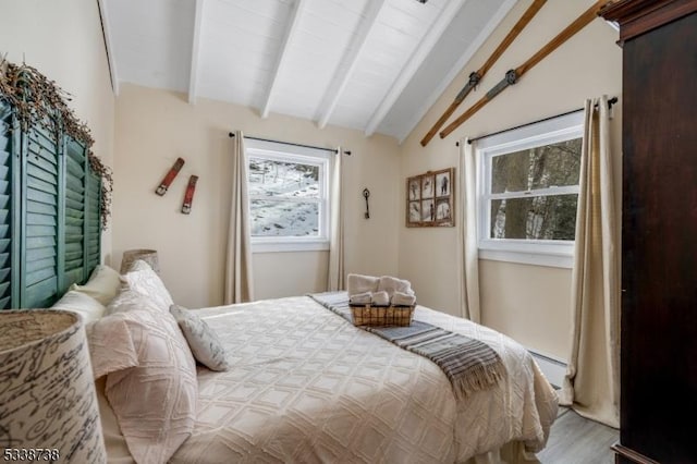 bedroom with lofted ceiling with beams, baseboard heating, and wood finished floors