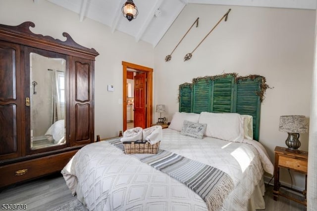 bedroom featuring lofted ceiling with beams and wood finished floors