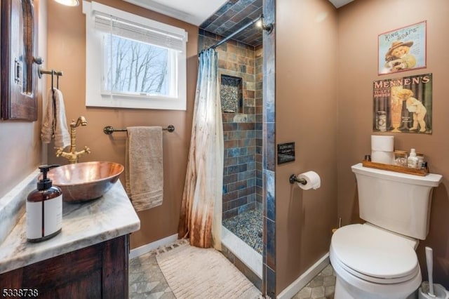 full bathroom featuring tiled shower, vanity, toilet, and baseboards