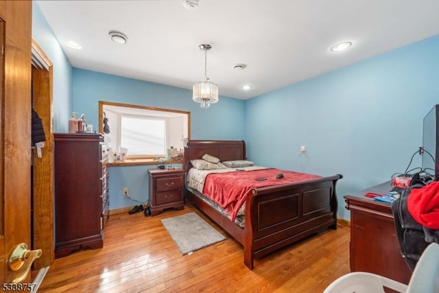 bedroom with an inviting chandelier and light hardwood / wood-style floors