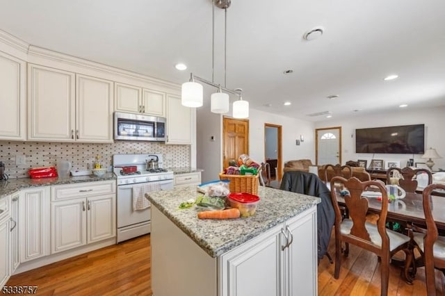 kitchen with pendant lighting, white gas range, light hardwood / wood-style floors, and a kitchen island