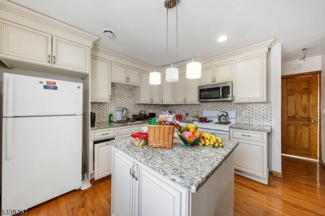 kitchen with white appliances, light hardwood / wood-style flooring, hanging light fixtures, and white cabinets