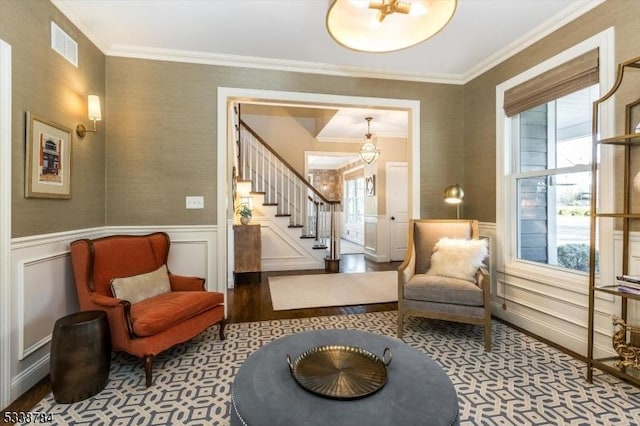 sitting room with a wainscoted wall, stairs, visible vents, and ornamental molding