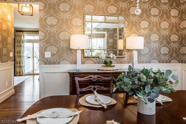 dining space with a healthy amount of sunlight, a wainscoted wall, wallpapered walls, and wood finished floors