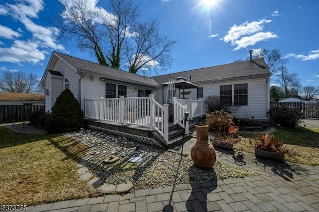 back of property featuring a yard, a wooden deck, and a patio area