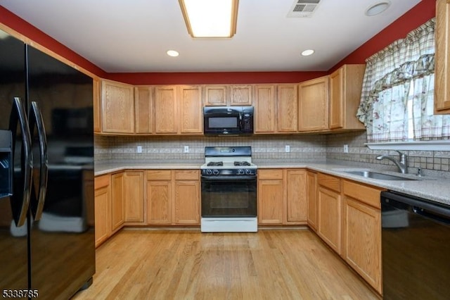 kitchen with light hardwood / wood-style floors, sink, black appliances, and tasteful backsplash