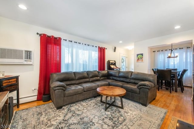 living room featuring a wall mounted air conditioner, light hardwood / wood-style flooring, and a baseboard radiator