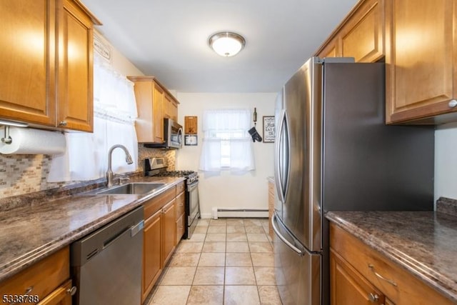 kitchen with light tile patterned floors, sink, a baseboard heating unit, stainless steel appliances, and decorative backsplash