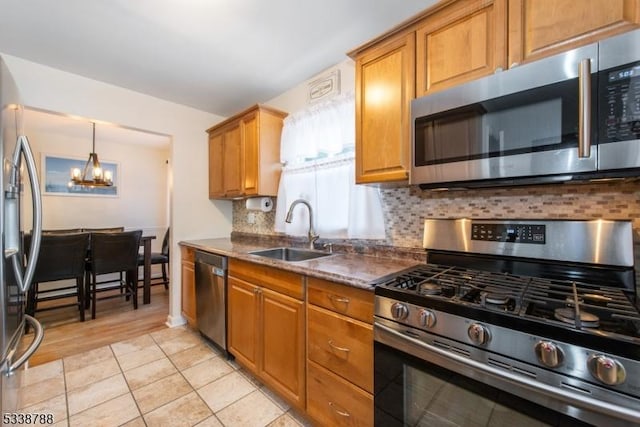 kitchen with appliances with stainless steel finishes, a notable chandelier, backsplash, light tile patterned floors, and sink