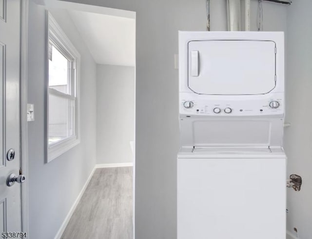 washroom with stacked washer and dryer and light hardwood / wood-style floors