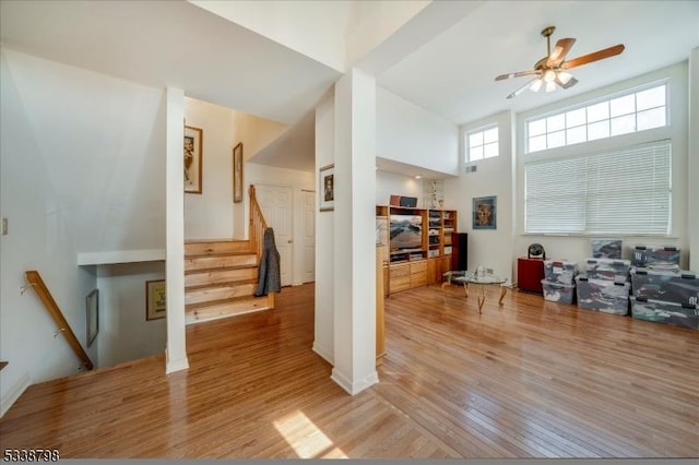 interior space featuring stairs, a high ceiling, light wood-type flooring, and a ceiling fan