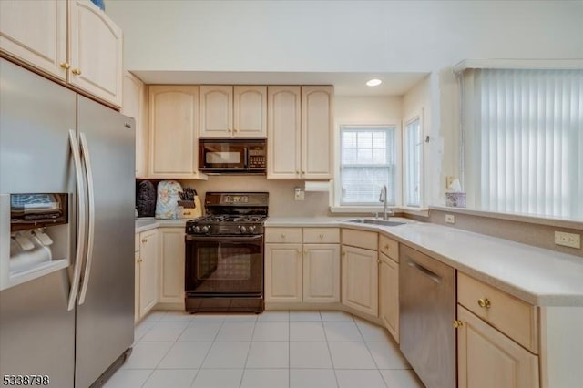 kitchen featuring a peninsula, black appliances, light countertops, and a sink