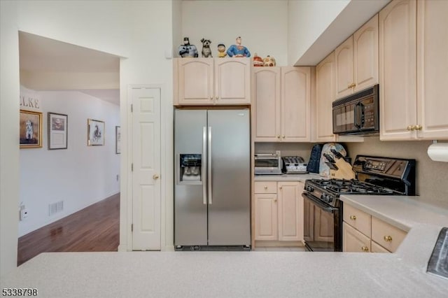 kitchen featuring wood finished floors, visible vents, light countertops, light brown cabinetry, and black appliances