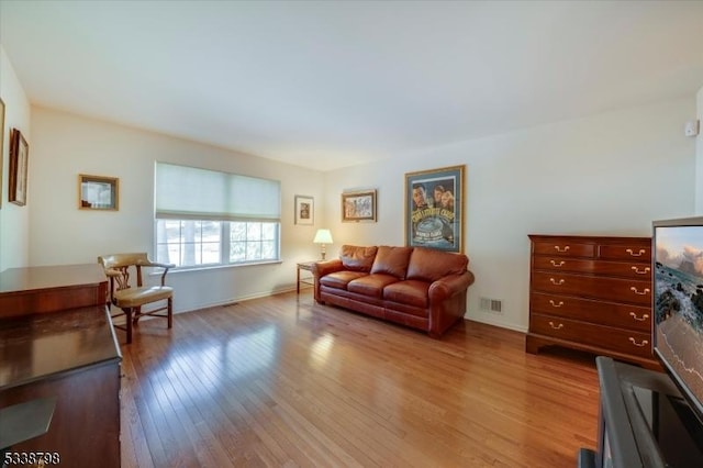 living area featuring baseboards, visible vents, and hardwood / wood-style floors