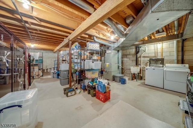 unfinished below grade area featuring heating unit, a sink, and independent washer and dryer