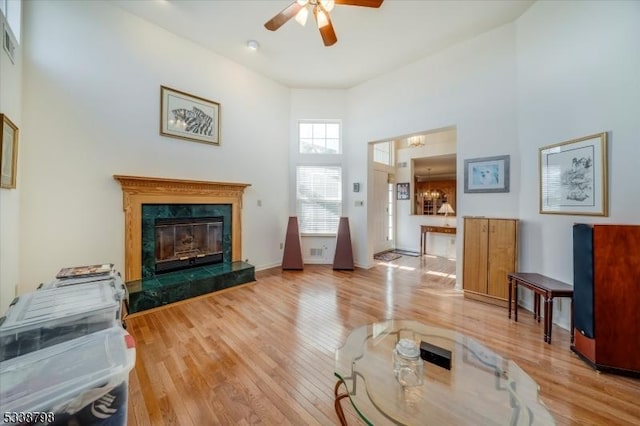 living room with hardwood / wood-style floors, a fireplace, a towering ceiling, and a ceiling fan