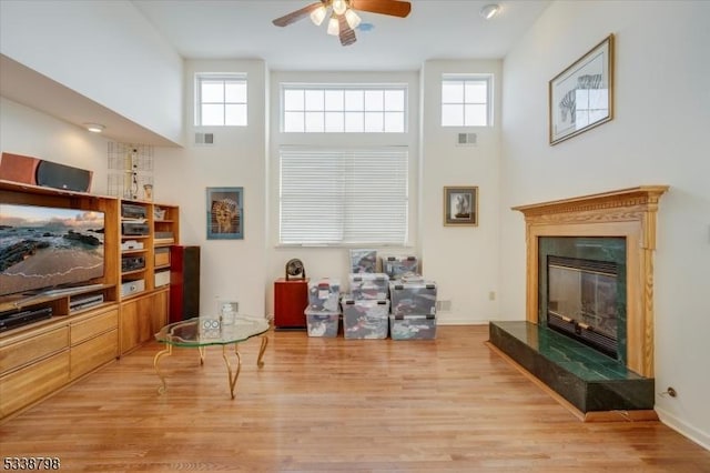 living room with ceiling fan, a glass covered fireplace, a wealth of natural light, and wood finished floors