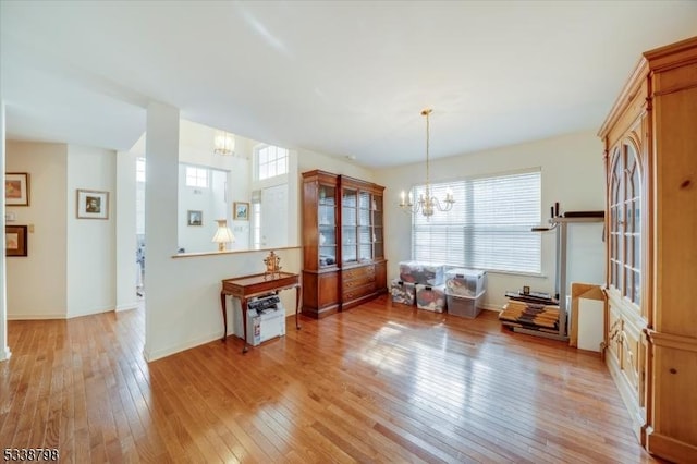 dining room featuring baseboards, a healthy amount of sunlight, light wood-type flooring, and an inviting chandelier