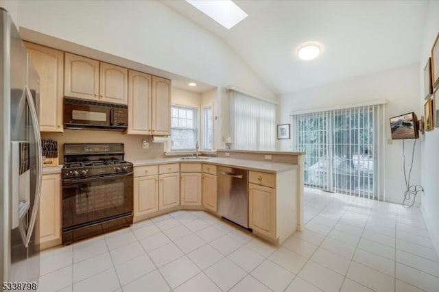 kitchen with a sink, black appliances, light brown cabinetry, and light countertops