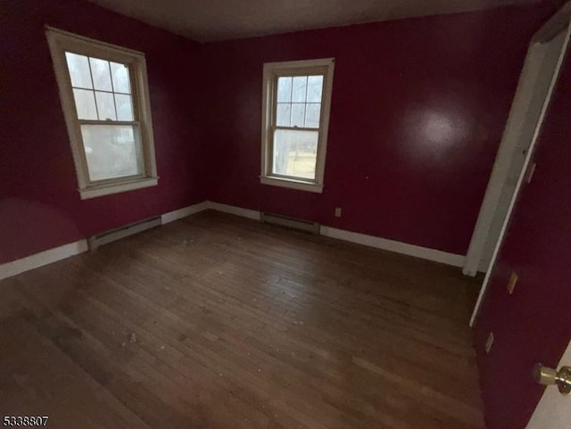 unfurnished bedroom with baseboard heating and dark hardwood / wood-style floors