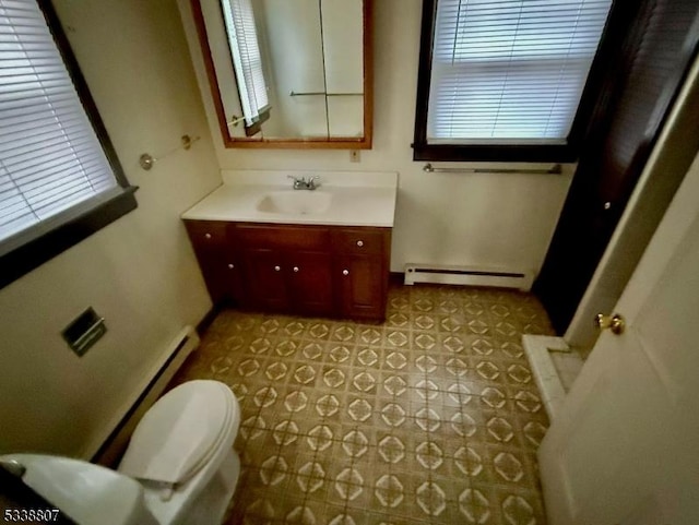 bathroom featuring a baseboard heating unit, toilet, vanity, and tile patterned flooring