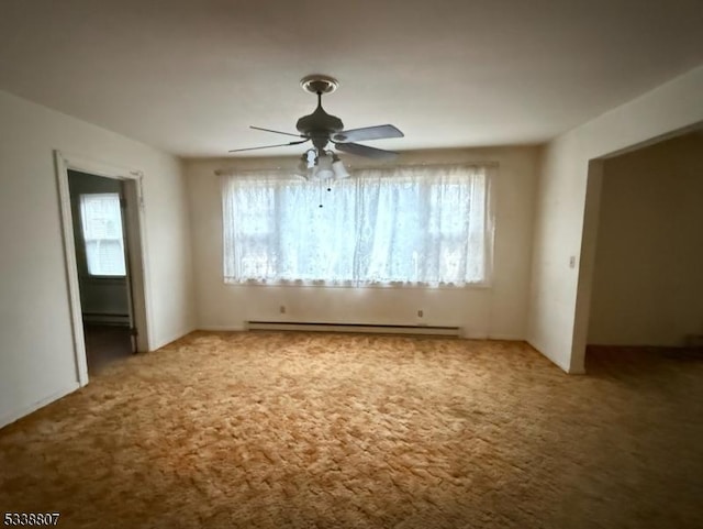 carpeted empty room featuring a wealth of natural light, ceiling fan, and a baseboard heating unit