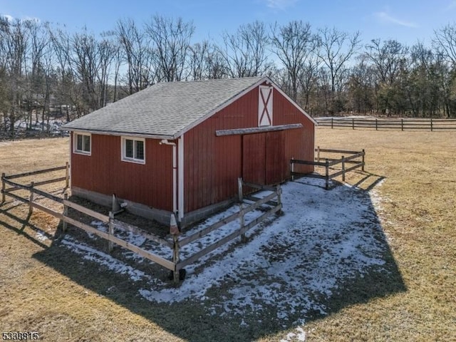 view of barn with a yard, fence, and a rural view