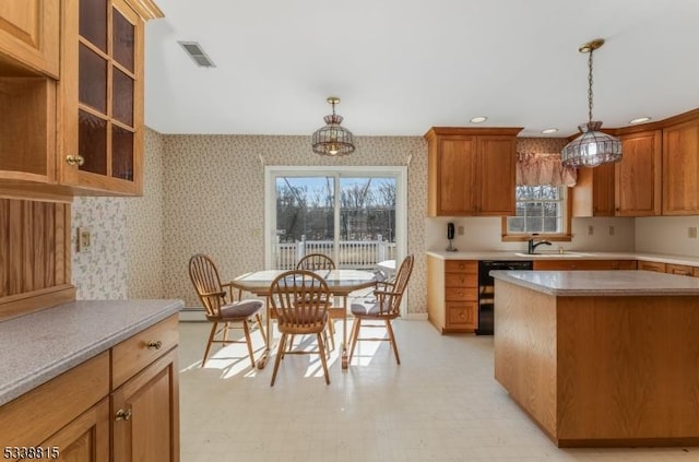 kitchen featuring visible vents, light countertops, dishwasher, glass insert cabinets, and wallpapered walls