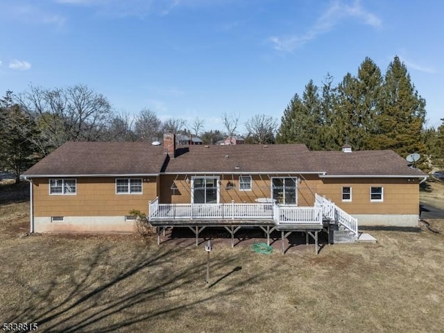 rear view of house with a yard, a chimney, and a wooden deck