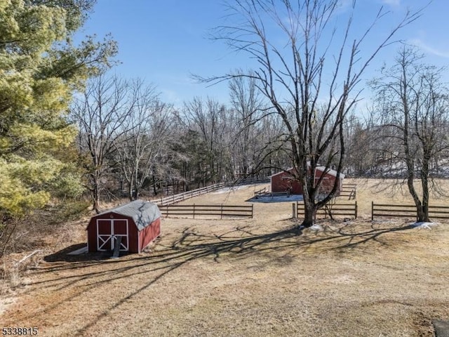 view of yard with an outbuilding, a rural view, fence, and a shed