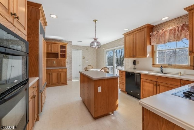 kitchen featuring light countertops, a center island, dishwasher, decorative light fixtures, and wallpapered walls