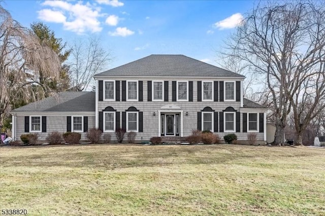 colonial house with a front lawn and roof with shingles