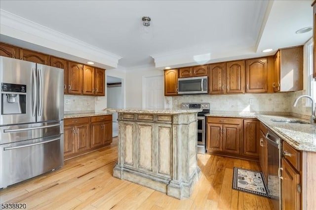 kitchen featuring decorative backsplash, light wood-style flooring, appliances with stainless steel finishes, brown cabinets, and a sink