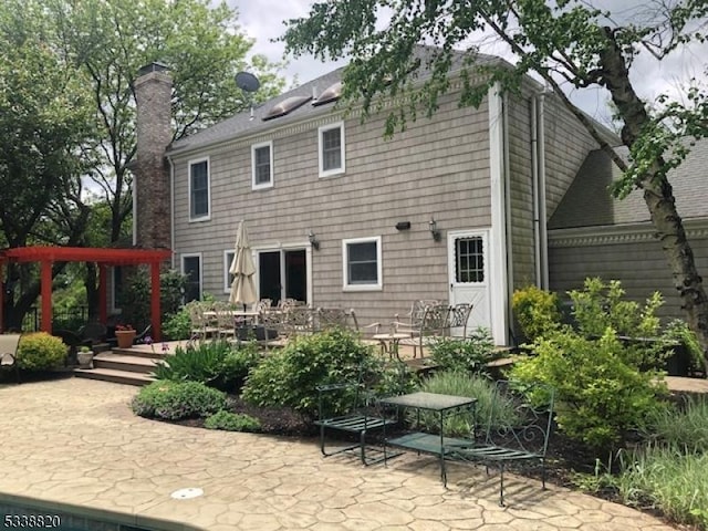 rear view of house featuring a patio area and a chimney