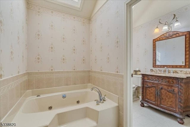 full bath with toilet, vanity, a tub with jets, and wallpapered walls