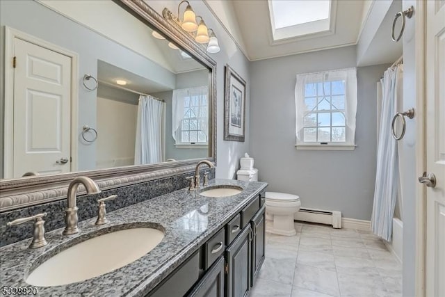 bathroom featuring toilet, a sink, baseboard heating, and double vanity