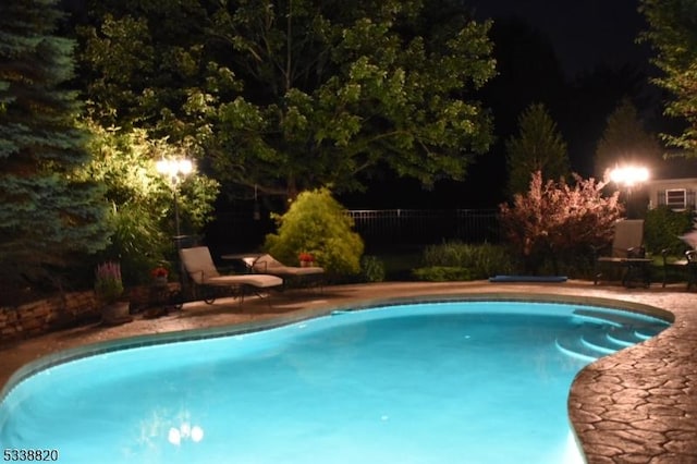 pool at twilight with an outdoor pool and fence