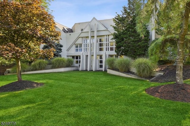 rear view of house with a lawn and stucco siding