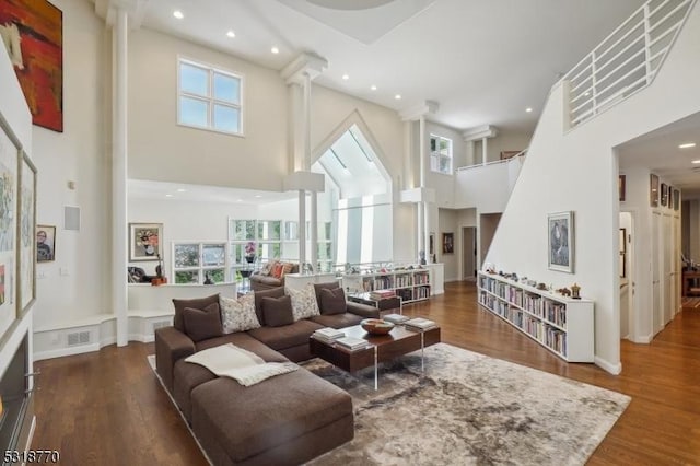 living area featuring dark wood-type flooring, plenty of natural light, a high ceiling, and recessed lighting