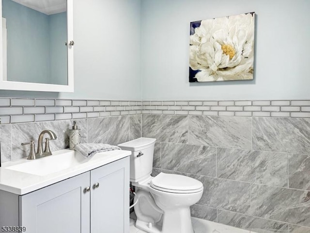 bathroom with tile walls, toilet, and vanity