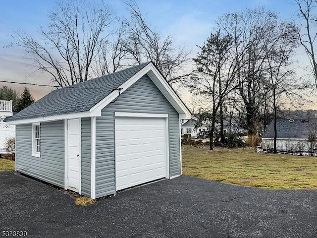 garage at dusk featuring a lawn